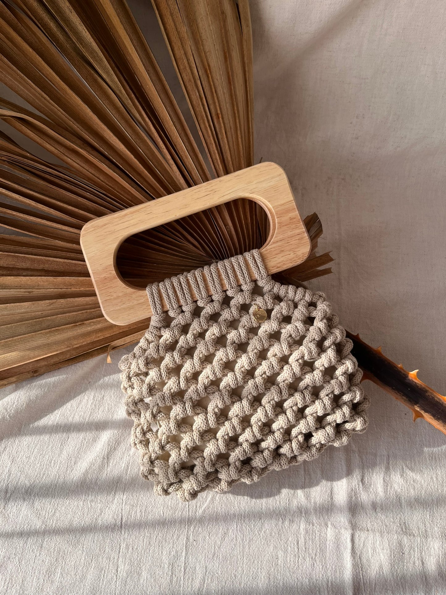 Handmade Koma Bag in Beige laying aesthetically on linen cloth