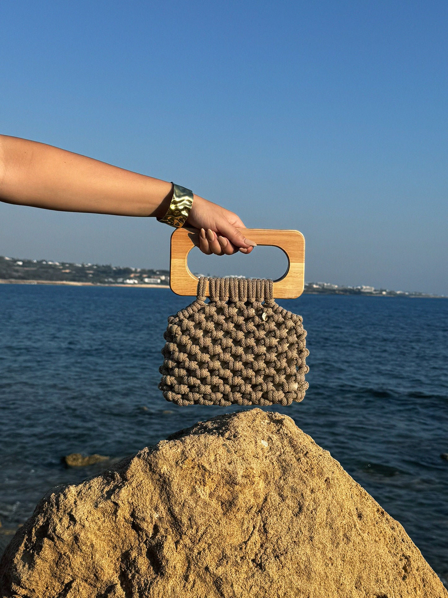 Handmade Koma Bag in Sand styled with gold bracelet.