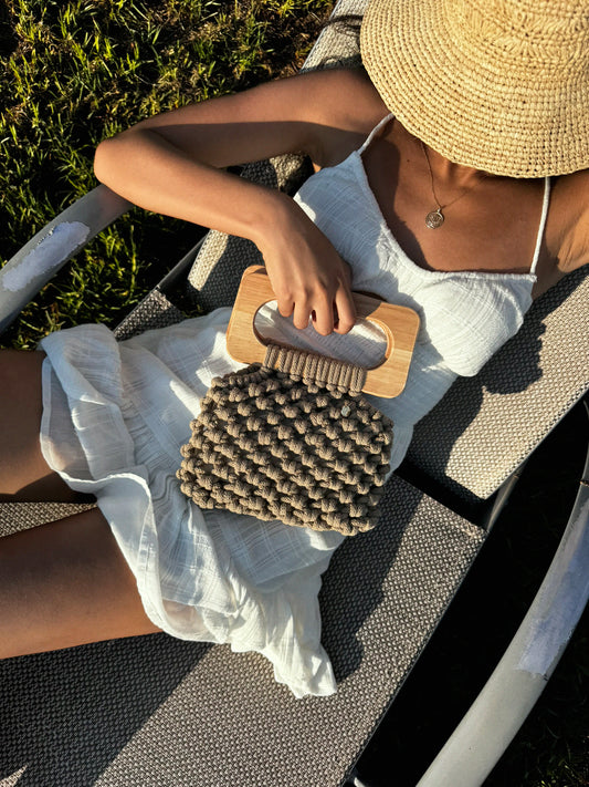 Handmade Koma Bag in sand beige cotton cord with wooden handles, styled in a summer white dress and a raffia sun hat.
