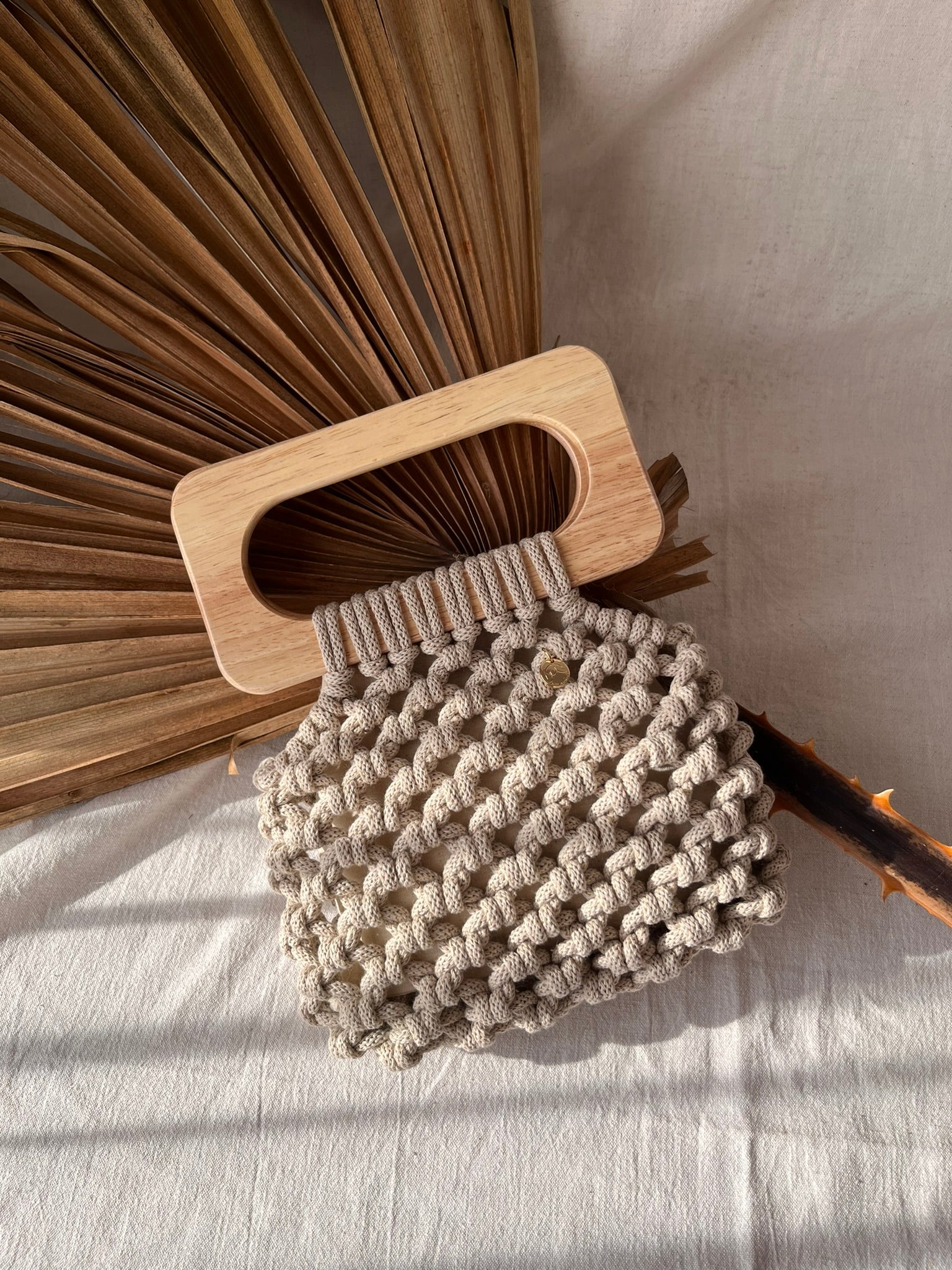 Handmade Koma Bag in Beige laying aesthetically on linen cloth